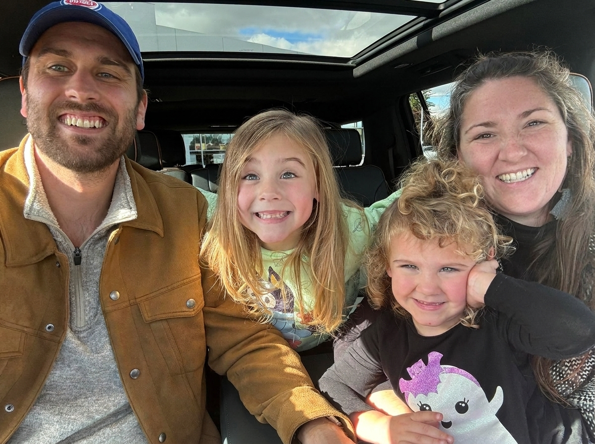 Carter, Courtenay, and their two daughters smiling together in the car
